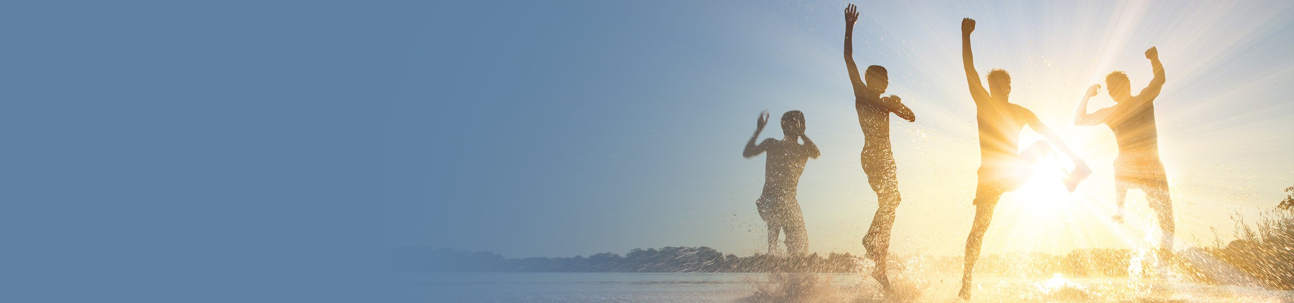 Im Wasser hüpfende Menschen mit strahlender Sonne im Hintergrund