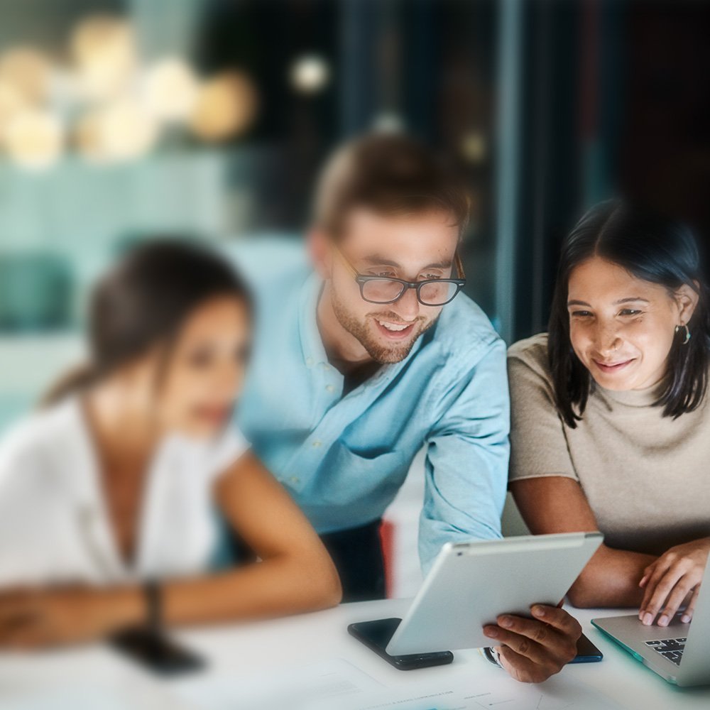 Drei Personen im Business-Kontext beugen sich über ihre Arbeit