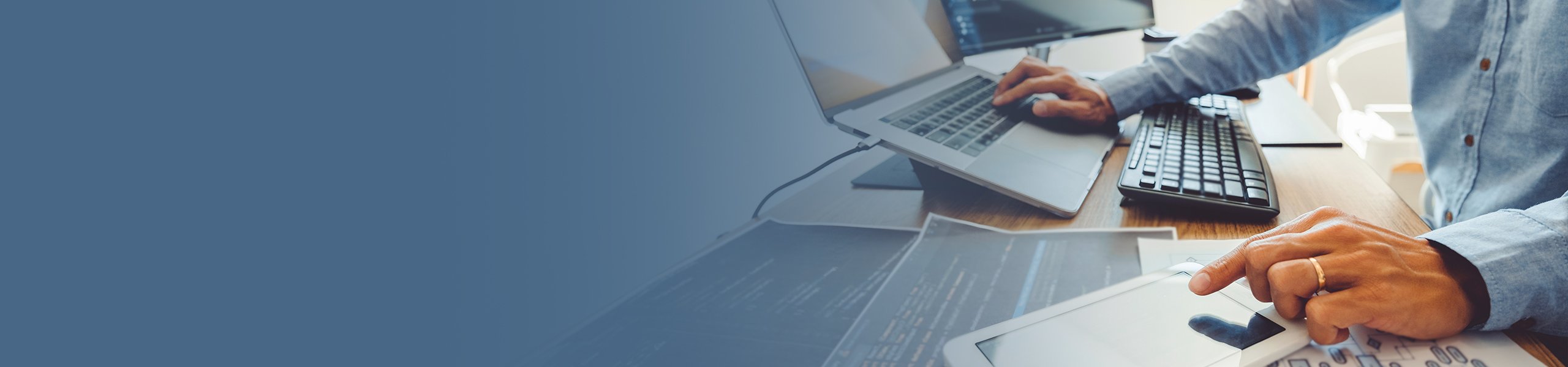 Eine Person bedient einen Laptop und ein Smartphone mit je einer Hand