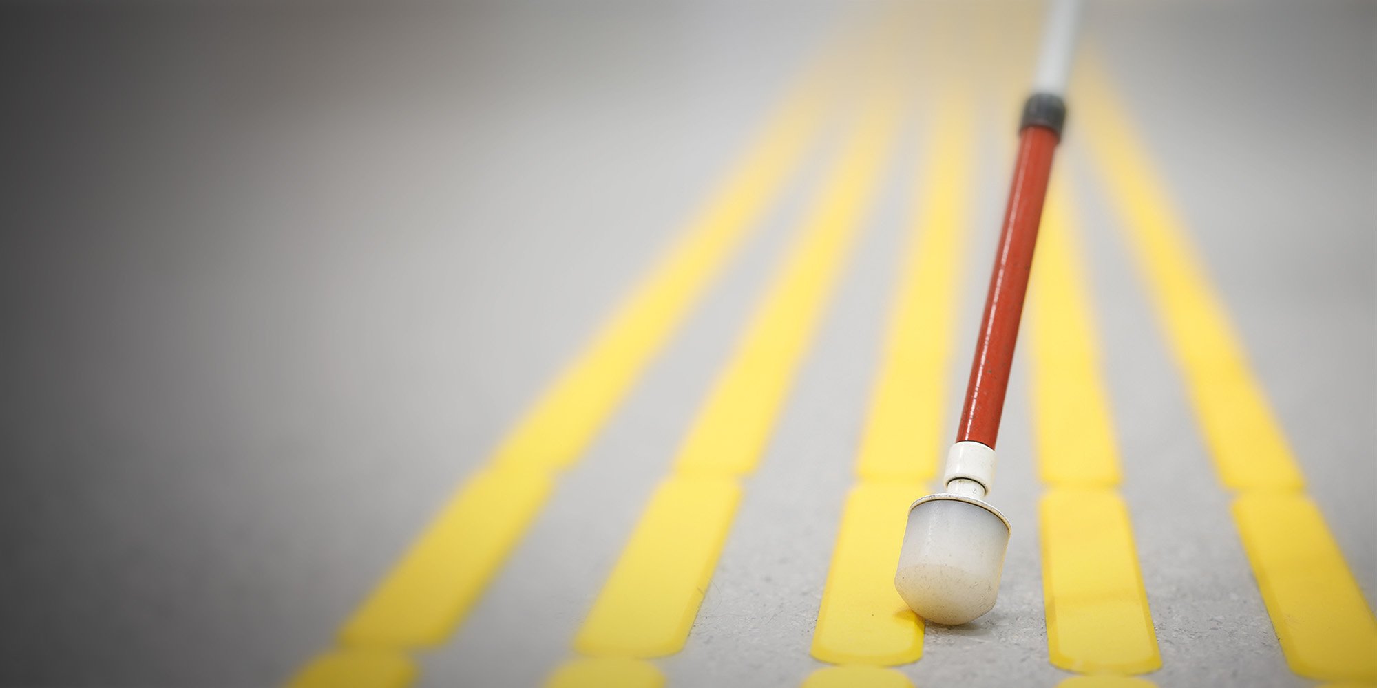 Nahaufnahme eines Langstocks auf einem Blindenleitsystem